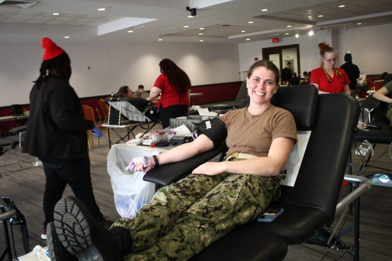 A student in uniform smiles at the camera while waiting for her blood donation to begin.